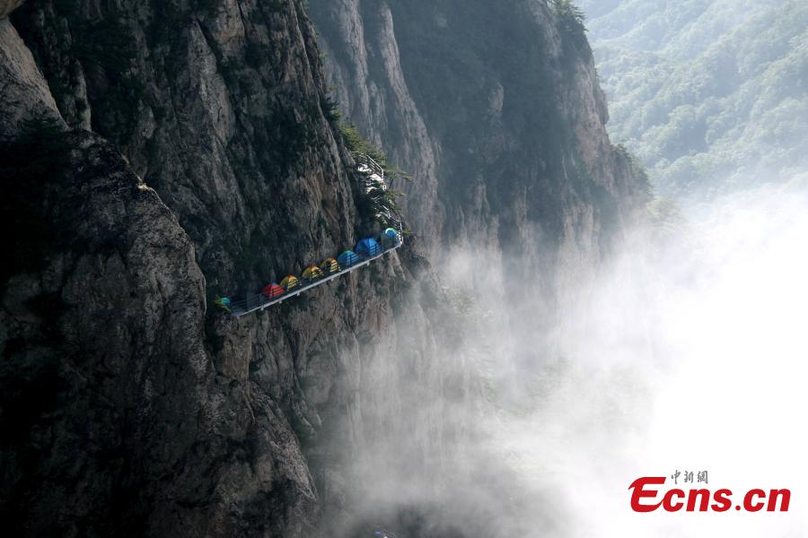 A line of tents on a suspended pathway built on the cliff, about 1,000 meters above the ground, at Laojun Mountain in Luoyang City, Central China’s Henan Province, July 16, 2016. The mountain is known for its cultural heritage relating to Taoism as it was once the retreat of Laozi, a great Chinese philosopher and the founder of Taoism. The mountain is hosting a tenting festival, which has attracted hundreds of tourists. (Photo: China News Service/Wang Zhongju)