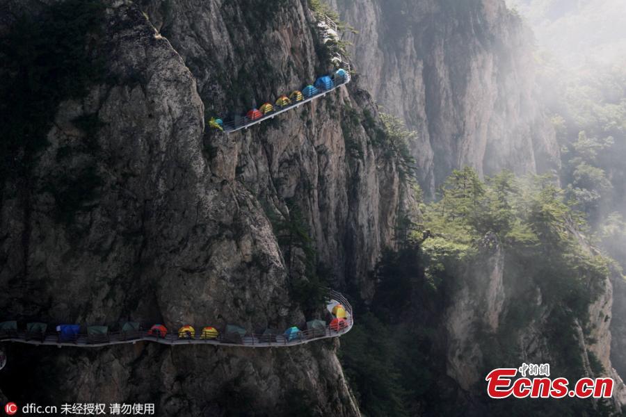 A line of tents on a suspended pathway built on the cliff, about 1,000 meters above the ground, at Laojun Mountain in Luoyang City, Central China’s Henan Province, July 16, 2016. The mountain is known for its cultural heritage relating to Taoism as it was once the retreat of Laozi, a great Chinese philosopher and the founder of Taoism. The mountain is hosting a tenting festival, which has attracted hundreds of tourists. (Photo: China News Service/Wang Zhongju)