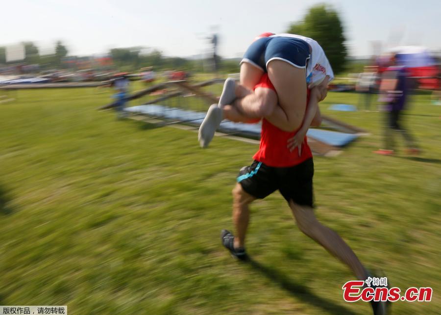 A man carries his wife while racing in the Wife Carrying competition to mark the City Day in Krasnoyarsk, Russia, June 10, 2018. (Photo/Agencies)