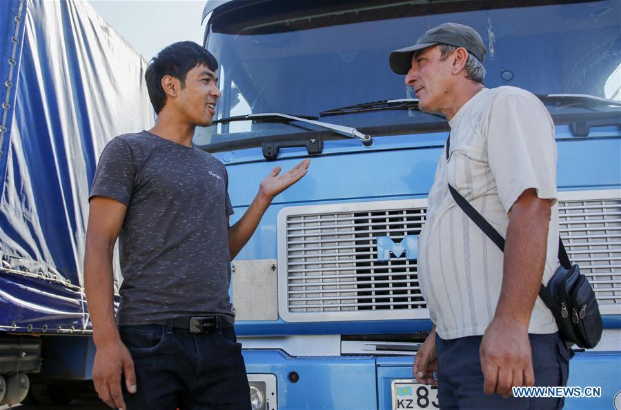 A driver from Kazakhstan (R) communicates with a Chinese translator in Horgos, northwest China\'s Xinjiang Uygur Autonomous Region, Aug. 4, 2018. The trade at the China-Kazakhstan Horgos International Border Cooperation Center enters a busy season since the beginning of the summer tourism peak. (Xinhua/Huang Zhen)