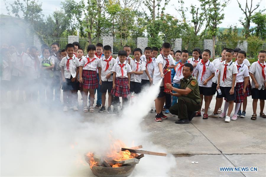 A fire fighter teaches a pupil from Chengguan No.1 Primary School to use extinguisher in Yuqing County of Zunyi City, southwest China\'s Guizhou Province, Aug. 27, 2018. Pupils from Chengguan No. 1 Primary School learnt knowledge of fire-fighting at the first day of the new semester. (Xinhua/He Chunyu)