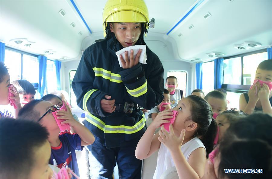 A fire fighter tells children how to escape in a drill of fire emergency at Xinhua District of Cangzhou City, north China\'s Hebei Province, Aug. 27, 2018. Children and students at Xinhua District participated in a drill of fire emergency before the new semester. (Xinhua/Fu Xinchun)