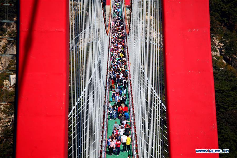 Tourists walk on a pedestrian suspension bridge built in the Yimeng mountains in Linyi, east China\'s Shandong Province, Oct. 3, 2018, the third day of the week-long National Day holiday. (Xinhua/Wu Jiquan)