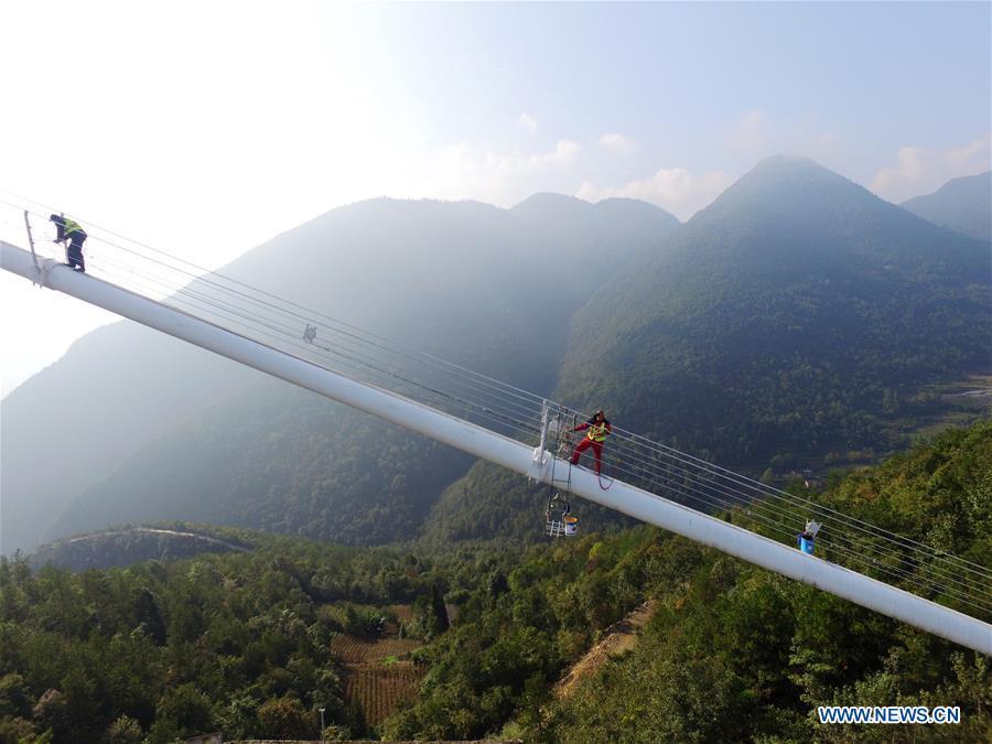 Staff members carry out cleaning and maintenance work on one of the main cables of the Sidu River Bridge in central China\'s Hubei Province, Oct. 10, 2018. The suspension bridge crosses the Sidu River valley near the boundaries of Yichang and Enshi in Hubei Province. The top point of the bridge is 650 meters above the bottom of the valley, a height comparable to a 200-storey skyscraper. (Xinhua/Zhu Wei)