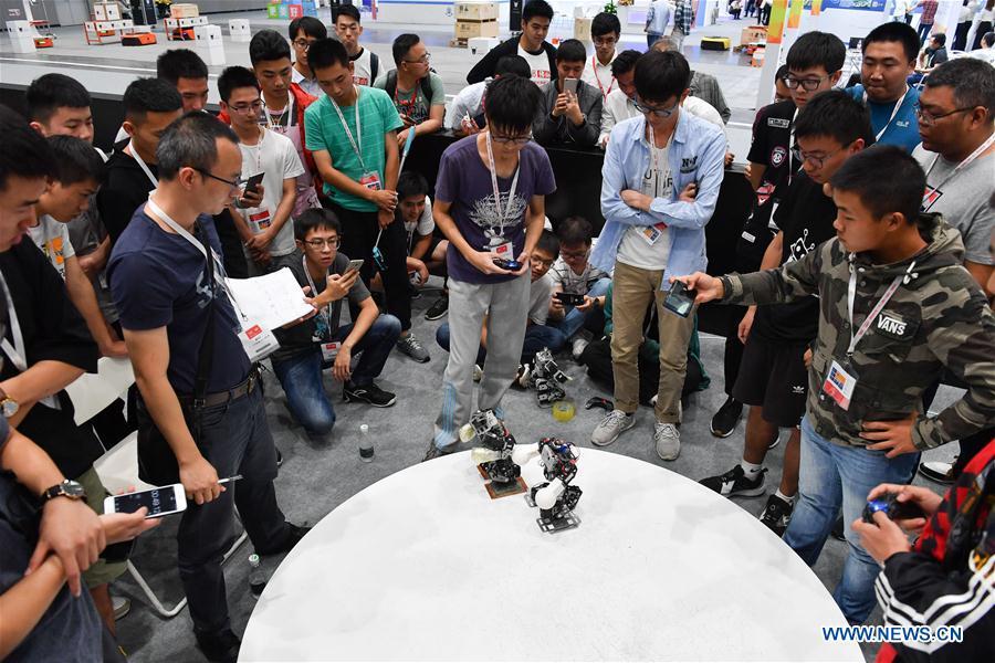 Visitors watch robots competing in boxing at the 20th National Robot and Artificial Intelligence Competition in Shunde District of Foshan, south China\'s Guangdong Province, Oct. 24, 2018. The 20th National Robot and Artificial Intelligence Competition kicked off here on Wednesday. More than 200 teams from 78 Chinese colleges will take part in 49 competitions under 13 categories. (Xinhua/Sadat)