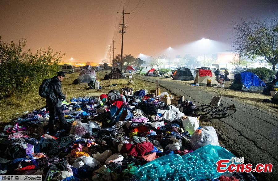 Evacuees sift through a pile of clothing at an evacuee encampment in a Walmart parking lot in Chico, California on November 17, 2018. More than 1,000 people remain listed as missing in the worst-ever wildfire to hit the US state.  (Photo/Agencies)