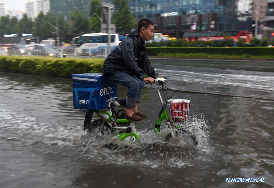 A food delivery courier makes his way along a flooded road after a downpour hit Beijing, capital of China, June 30, 2018. China\'s express delivery sector handled 50.5 billion parcels in 2018, up 25.8 percent year on year, data from the State Post Bureau (SPB) showed. Gross business revenue of the sector increased 21.2 percent year on year to hit 601 billion yuan (about 88 billion U.S. dollars) last year, according to the SPB. (Xinhua/Luo Xiaoguang)