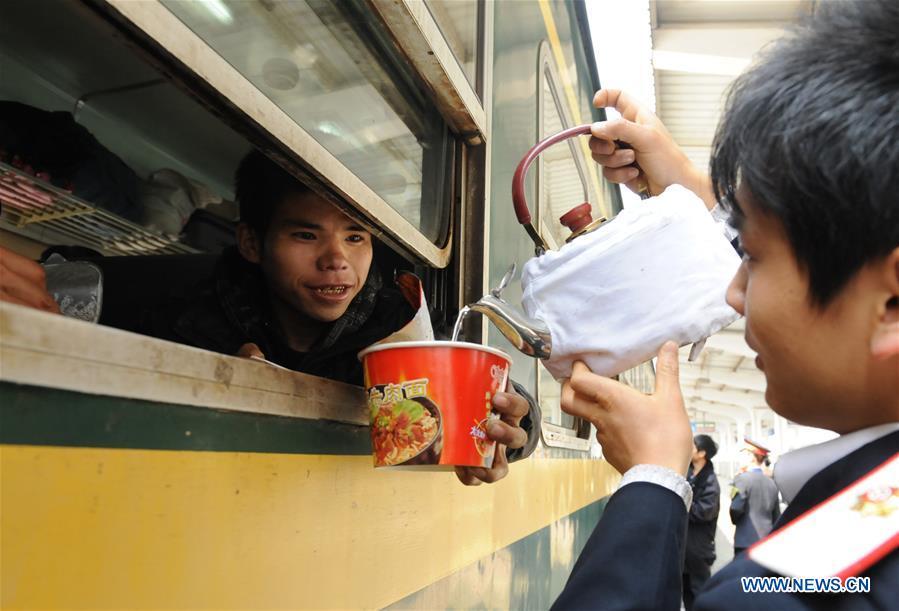 File photo taken on March 10, 2010 shows a railway staff member pouring hot water for a passenger on the platform of Guiyang Railway Station in Guiyang, southwest China\'s Guizhou Province. Platforms, witnessing memorable moments of joy and sadness, are the epitome of each year\'s Spring Festival travel rush, during which hundreds of millions of Chinese go back to their hometowns for family gatherings. (Xinhua/Yang Junjiang)