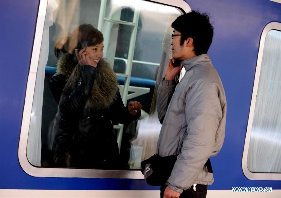 File photo taken on Jan. 23, 2009 shows a couple saying goodbye through the window on mobile phones at Zhengzhou Railway Station, central China\'s Henan Province. Platforms, witnessing memorable moments of joy and sadness, are the epitome of each year\'s Spring Festival travel rush, during which hundreds of millions of Chinese go back to their hometowns for family gatherings. (Xinhua/Zhu Xiang)