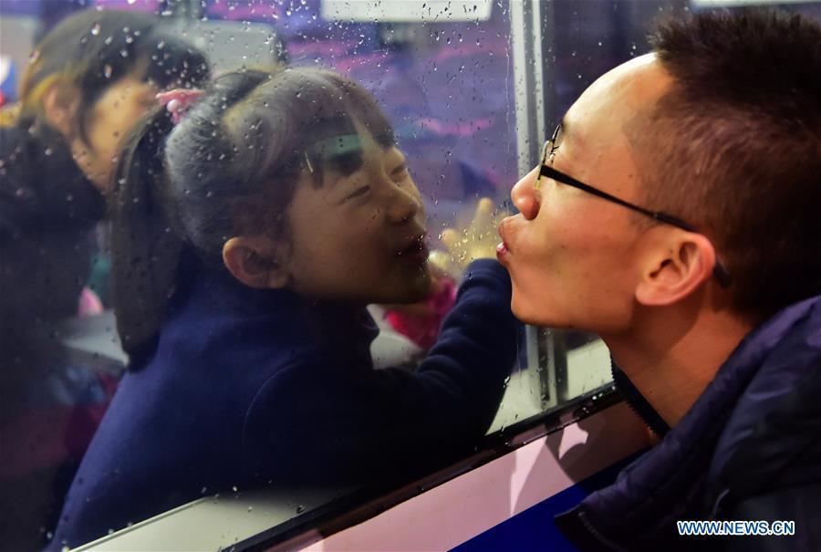 File photo taken on Jan. 13, 2017 shows migrant worker Luo Jiang (R) trying to kiss his daughter goodbye through the window of a train at the Fuzhou Railway Station in Fuzhou, capital of southeast China\'s Fujian Province. Platforms, witnessing memorable moments of joy and sadness, are the epitome of each year\'s Spring Festival travel rush, during which hundreds of millions of Chinese go back to their hometowns for family gatherings. (Xinhua/Wei Peiquan)