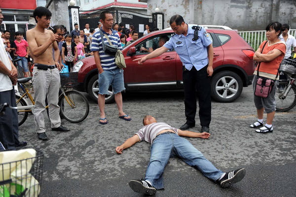 A man lies on his back in protest against the closure of a private school where his child was attending in Houbajia village, Haidian district on Monday. [PHOTO/CHINA DAILY]