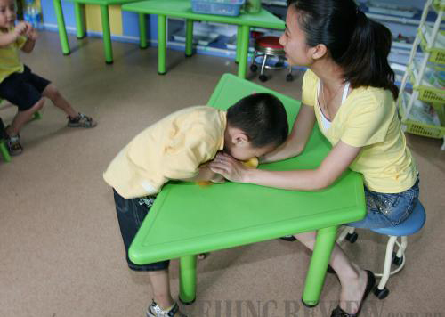 YOUNG PATIENT: An autistic child clutches the toy in a teacher's hand in an autism rehabilitation center in Guangzhou, Guangdong Province. Such children usually are impaired in social interaction and communication (CFP)