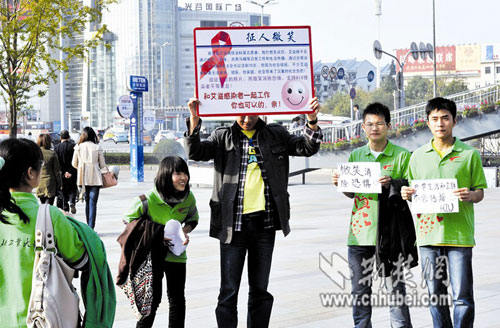 Mr. Ma, 36, an HIV carrier from Henan, invites passers-by to take smiling photos with him, together with university volunteers in Wuhan, central China's Hubei province, November 21. 