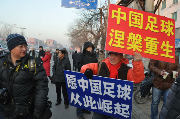 Two soccer fans raise posters that read: Rebirth of Chinese soccer and Don't let fans down again on Monday at the gate of the Tieling Intermediate People's Court. Provided to China Daily