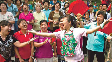 A woman leads the singing of patriotic songs, at Beijing's Jingshan Park on Tuesday, to celebrate the upcoming 90th anniversary of the founding of the Communist Party of China on July 1. (AP Photo)