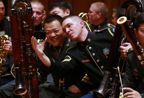 Military musicians from China and the US record a noteworthy moment during a joint rehearsal by the US army and PLA bands at the National Center for the Performing Arts in Beijing on Monday. Feng Yongbin / China Daily