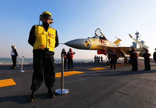 This undated photo shows staff members checking a carrier-borne J-15 fighter jet on China's first aircraft carrier, the Liaoning. China has successfully conducted flight landing on its first aircraft carrier, the Liaoning. [Xinhua]