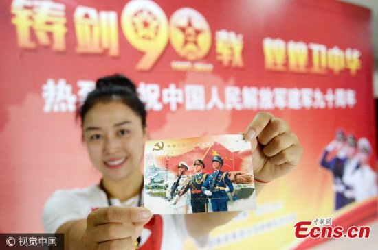 A woman shows a miniature sheet as part of a commemorative set of stamps issued to mark the 90th anniversary of the founding of the Peoples Liberation Army in Handan City, North Chinas Hebei Province, Aug. 1, 2017. (Photo/VCG)