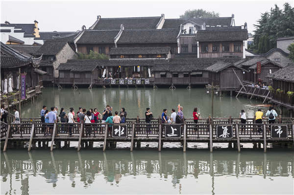 Crisscrossing waterways are now the biggest draw for visitors to Wuzhen, Zhejiang province. Visitors stroll along the banks or hop aboard boats to take in the views. (Photo by Shi Kuihua/For China Daily)