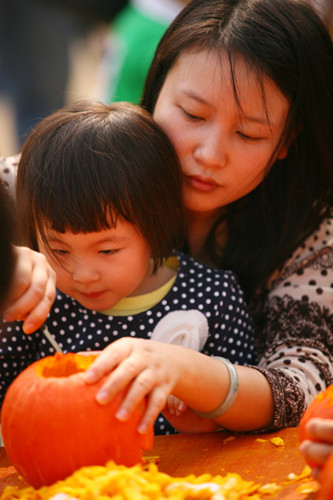 A girl carves a pumpkin lantern with her mother for Halloween at the Gulin Park in Nanjing, East China's Jiangsu province, Oct 28, 2012. [Photo/Asianewsphoto]