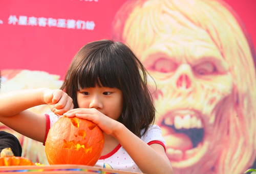 A girl carves a pumpkin lantern for Halloween at the Gulin Park in Nanjing, East China's Jiangsu province, Oct 28, 2012. [Photo/Asianewsphoto]