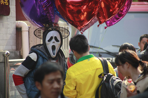 A man wears a Halloween mask to attract customs at Furong street in Jinan, East China's Shandong province, Oct 28, 2012. Local shops have prepared decorations and pumpkin lanterns for the upcoming Halloween. [Photo/Asianewsphoto]