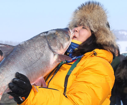 A female tourist is elated on buying the fish of her choice, at an ice-fishing event. [Photos by Bai Shi / For China Daily]