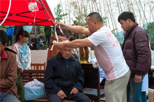 A volunteer helps an injured man bandage a wound in Baosheng township, Ya'an city, Sichuan province, April 21. [Photo/Xinhua]