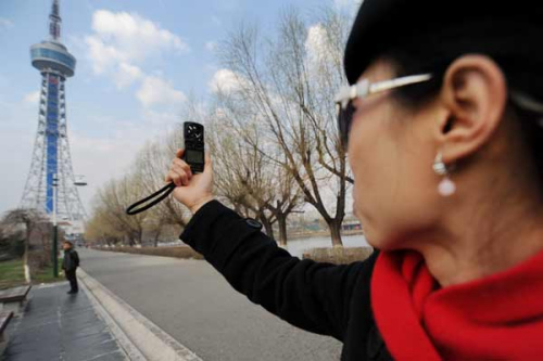 Jia Mingyou (R) measures wind speed before controlling an air vehicle to take aerial photos in Changchun, Northeast China's Jilin province, May 3, 2013. [Photo/Xinhua]