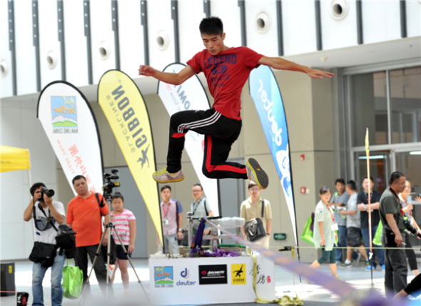 Outdoor enthusiasts jump, rotate and flip on a 5cm-wide rope at the 8th Asia Outdoor Trade Show at Nanjing International Expo Center in the capital of East Chinas Jiangsu province, on July 24. Extreme outdoor sports fans turned the tight rope-walking into an extreme sport and developed a set of synchronized stunts. [You You/Asianewsphoto]