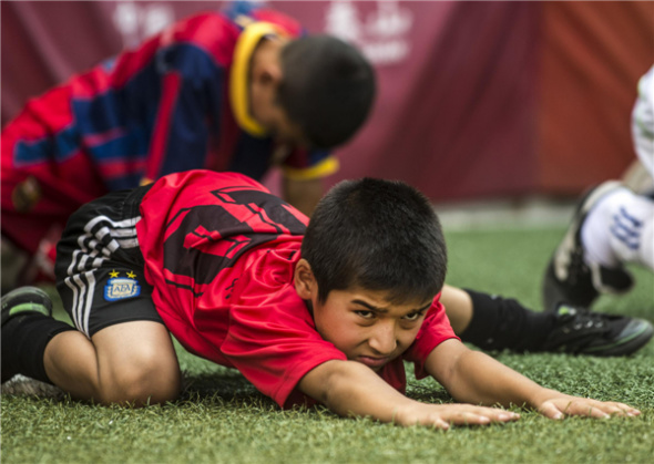 Student soccer players from Urumqi Fifth Primary School stretch in preparation for trainings on Aug 13 in Urumqi, Xinjiang Uygur autonomous region. [Photo/Xinhua]