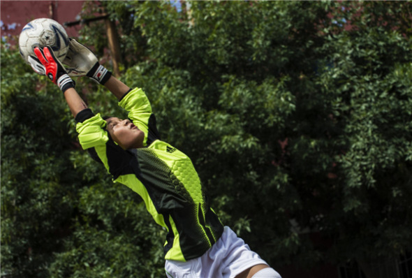 The goalkeeper from Urumqi Fifth Primary School soccer team catches a ball during training in Urumqi, Xinjiang Uygur autonomous region on Aug 13. [Photo/Xinhua]