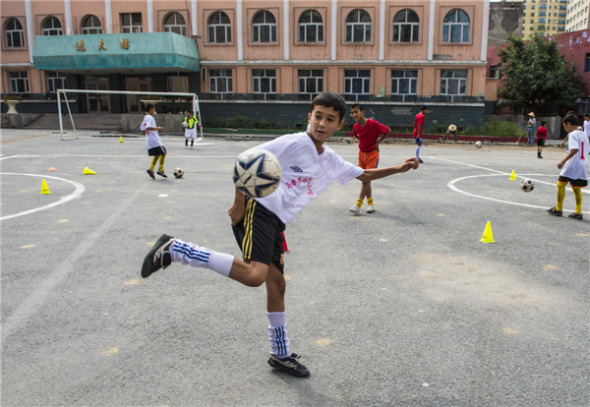 Student soccer ball players from Urumqi Fifth Primary School train on Aug 13 in Urumqi, Xinjiang Uygur autonomous region. [Photo/Xinhua]