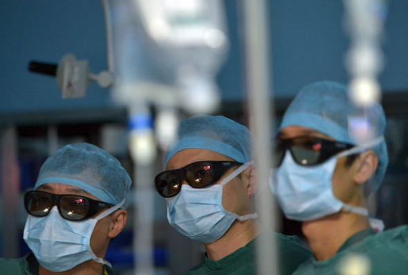 Doctors wearing 3D glasses perform a radical gastric cancer operation at Tongji Hospital in Wuhan, Central China' Hubei province, Aug 22, 2013. [Photo/Asianewsphoto]