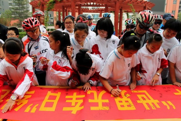 Students sign their names on a banner promoting World Car-free Day at a bicycle club in Xingtai city, North Chinas Hebei province, Sept 22. [Photo/Xinhua]