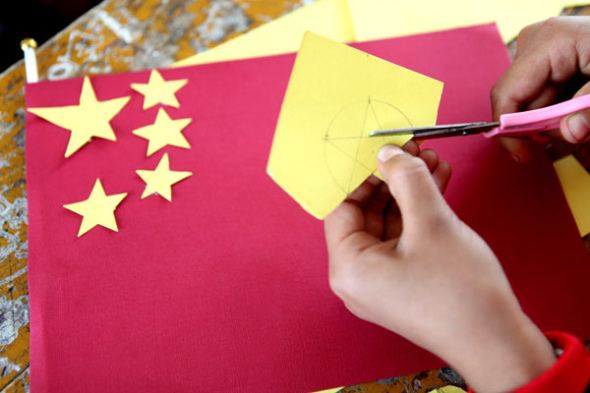 A student cuts the pieces to make a national flag at a primary school in Bozhou, East China's Anhui province, Sept 26, 2013. October 1 marks the 64th anniversary of the founding of People's Republic of China. [Photo/Asianewsphoto]