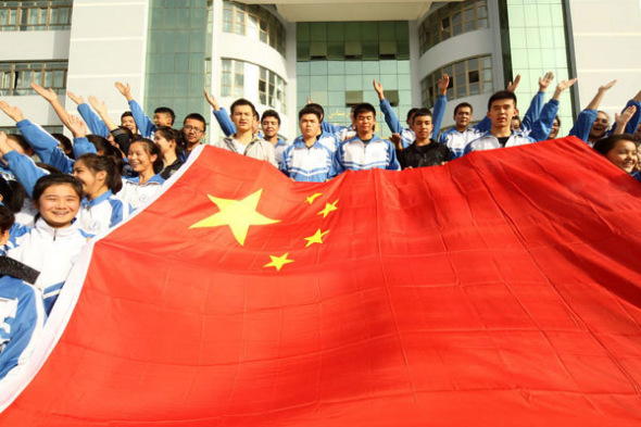 College students pose with a national flag to celebrate National Day on Oct 1 in Hami, Xinjiang Uygur autonomous region, Sept 26, 2013. [Photo/Asianewsphoto]