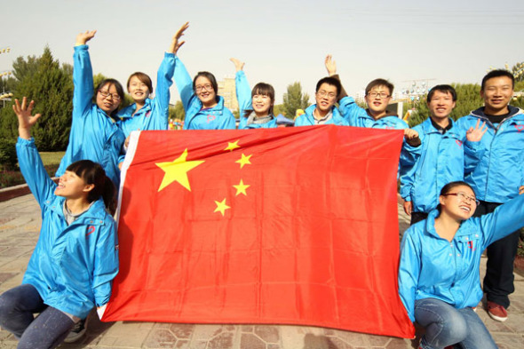 College students pose with a national flag to celebrate the National Day on Oct 1 in Hami, Xinjiang Uygur autonomous region, Sept 26, 2013. [Photo/Asianewsphoto]