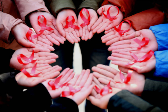 College students in Bozhou, Anhui province, show their handmade AIDS ribbons to call for the elimination of discrimination against people with AIDS, Nov 28, 2013. [Photo by Liu Liqin/Asianewsphoto]