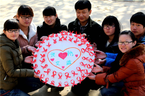 College students in Bozhou, Anhui province, show their handmade AIDS ribbons to call for the elimination of discrimination against people with AIDS, Nov 28, 2013. [Photo by Liu Liqin/Asianewsphoto]