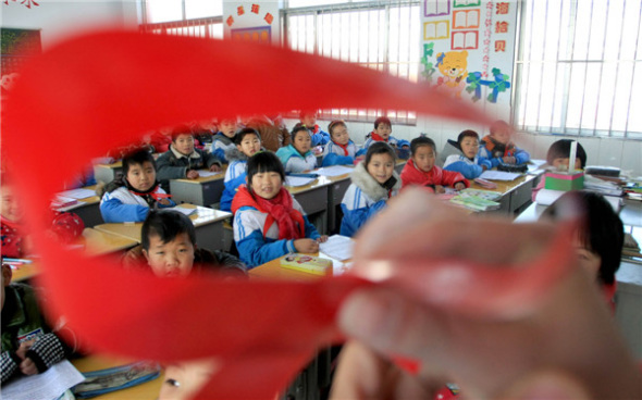 Primary school students in Donghai county, Jiangsu province, listen to a medical worker explaining HIV, Nov 29, 2013. [Photo by Zhang Kaihu/Asianewsphoto]