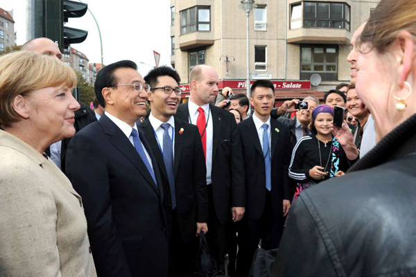 Premier Li Keqiang, accompanied by German Chancellor Angela Merkel, meets local residents on a Berlin street on Oct 10, 2014. [Photo/Xinhua]