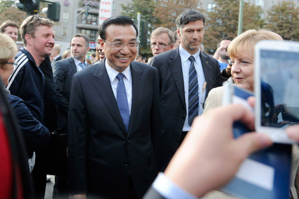 Premier Li Keqiang, accompanied by German Chancellor Angela Merkel, meets local residents on a Berlin street on Oct 10, 2014. [Photo/Xinhua]