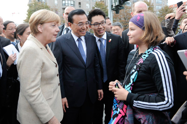 Premier Li Keqiang, accompanied by German Chancellor Angela Merkel, talks with local residents on a Berlin street on Oct 10, 2014. [Photo/Xinhua]