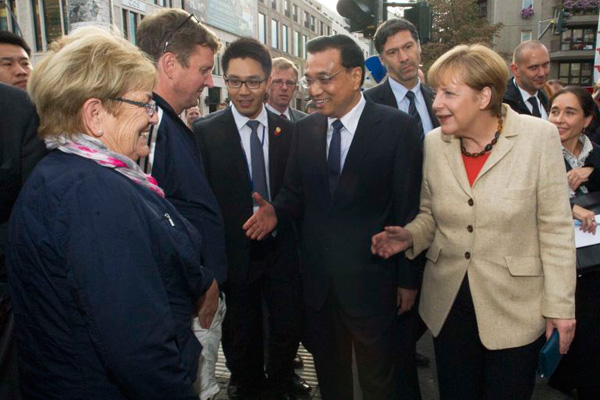 Premier Li Keqiang, accompanied by German Chancellor Angela Merkel, talks with local residents on a Berlin street on Oct 10, 2014. [Photo/Xinhua]