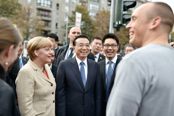 Premier Li Keqiang, accompanied by German Chancellor Angela Merkel, talks with local residents on a Berlin street on Oct 10, 2014. [Photo/Xinhua]