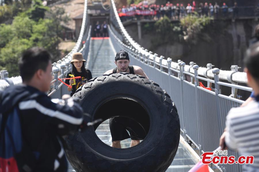 Tire flip challenges strongmen on suspended glass bridge 
