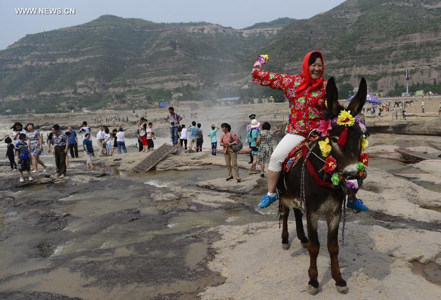 
A woman pose for a photo near the Hukou Waterfall of the Yellow River in  Yichuan County, northwest China\'s Shaanxi Province, June 2, 2014. (Xinhua/Liu  Xiao)