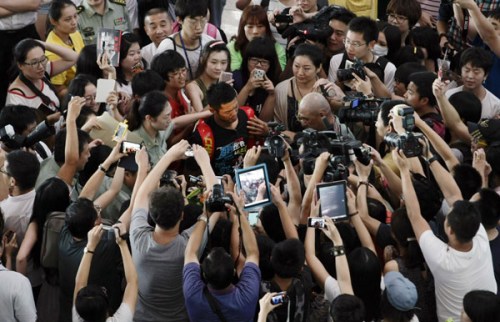 Journalists and sports fans greet badminton gold medalist Lin Dan at Beijing Capital International Airport on Thursday. 