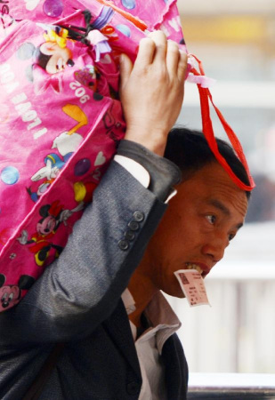 File photo taken on Jan. 25, 2013 shows a passengers with a train ticket in his mouth carries his luggage before boarding a train at Nanchang Railway Station in Nanchang, east China's Jiangxi Province. China's transportation system has to undergo a challenge during every Spring Festival holidays, which sees a huge number of people take to the roads for family reunions. To have reunion dinner with their families on Chinese New Year's Eve, those who have worked or studied away from home scramble to leave for their hometowns by all means -- train, coach, airplane, ship, self-driving, motorcycles and even bicycles, making the largest annual human migration in the world. Chinese Lunar New Year, or the Spring Festival, falls on Feb. 10 this year, making the holiday travel period spanning from Jan. 26 to March 6. A record 3.41 billion trips are expected to be made over this year's Lunar New Year travel rush. (Xinhua/Zhou Ke) 